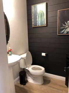 a white toilet sitting in a bathroom next to a sink and painting on the wall