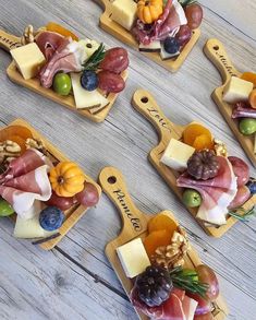 four wooden trays with different types of cheese and fruit arranged on top of each other