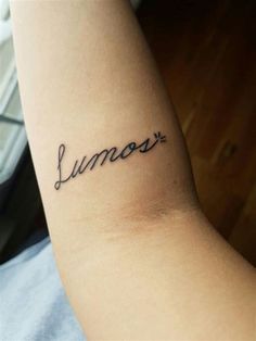 a woman's arm with the word lumos written in cursive font