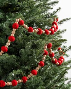 a close up of a christmas tree with red and white balls hanging from it's branches