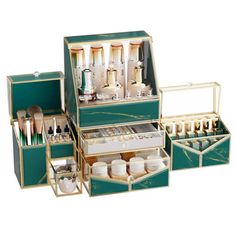 an assortment of cosmetics and makeup brushes in a green box with gold trimmings