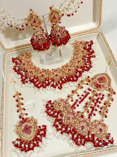 a white box with some red and gold jewelry in it's display case on a table