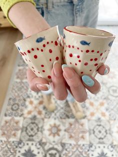 a woman holding two cups in her hands