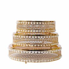 three rows of gold and white bangles with pearls on them, all stacked together