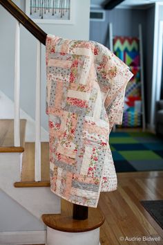 a quilted blanket is hanging on the banister