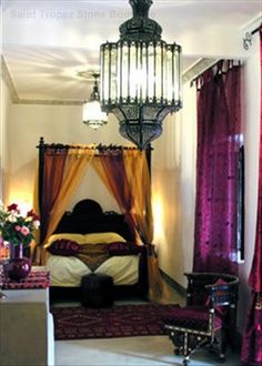 a bedroom with a canopy bed, chandelier and purple drapes on the windows