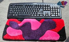 a computer keyboard sitting on top of a colorful mouse pad next to a black keyboard