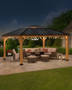 a gazebo sitting on top of a patio next to a lush green field at night