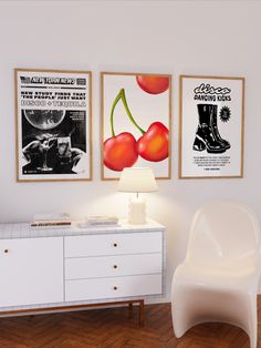 a white chair sitting next to a lamp on top of a wooden floor in front of two posters