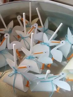 some white birds are tied with blue string and sitting in a metal bowl filled with water