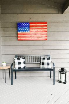 a bench sitting on top of a wooden floor next to a flag painted on the wall