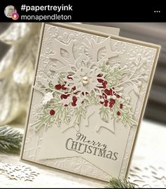 a white christmas card with red and green poinsettis on it, next to a pine tree