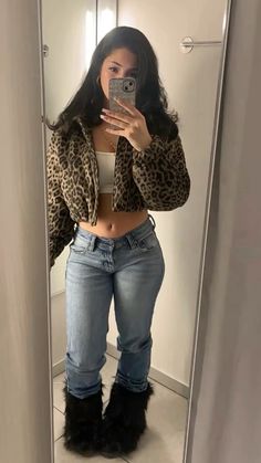 a woman is taking a selfie in the mirror with her cell phone while wearing leopard print jacket and jeans