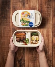 a person holding a container with food in it on top of a wooden table next to another container