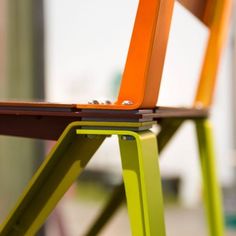 an orange and green chair sitting on top of a wooden table