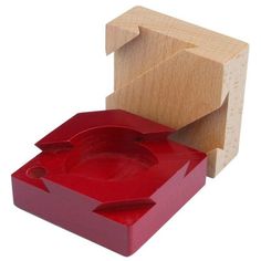 a wooden block with a red object in the middle and a piece of wood next to it