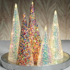 three small glitter trees are on a silver platter with colorful sprinkles