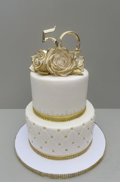 a white and gold wedding cake with roses on top