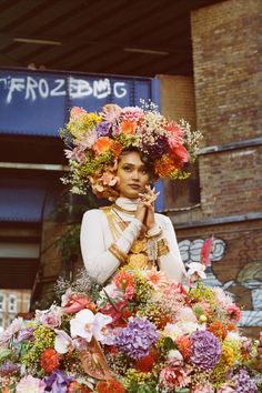 a woman with flowers on her head standing in front of a building