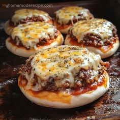 four mini pizzas with cheese and meat on them