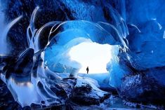 a man standing in an ice cave looking at the water