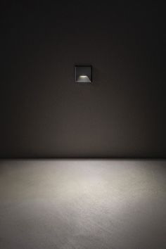 an empty room with a square light on the wall