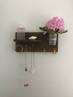 there is a vase with flowers and jewelry on the shelf next to the wall mounted necklace holder