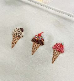 three ice cream cones are embroidered onto a white shirt