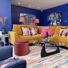 a living room with blue walls and colorful furniture in the center, including a yellow couch