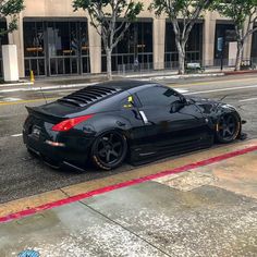 a black sports car is parked on the side of the road in front of a building