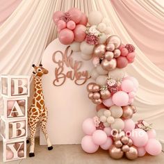 a giraffe standing next to a tall balloon arch