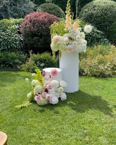 two white vases filled with flowers sitting in the grass