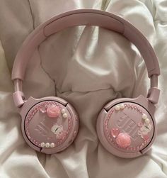 pink hello kitty headphones laying on top of a white bed with pearls and bows