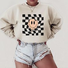 Smiley Face Crewneck Sweatshirt | Checkered Pattern Sweater | Trendy Crewneck Sweater | Retro Sweatshirt | Groovy Clothing | Distressed Vintage Sweater | Preppy Fashion | Gift for Her Simple Pixel Design creates unique + trendy merchandise, clothing & digital prints! Our sweatshirts are cozy and comfy - the perfect purchase to stay trendy while still dressing in comfort! HOW TO ORDER // Simply choose the color & size then add to cart! If you would like to purchase multiple sweatshirts, repeat the selection & put each item in the cart separately. INFO // * Gildan Unisex Crewneck Sweatshirt * 50% Cotton, 50% Polyester * Collar is ribbed knit // Retains its shape even after washing * Design is high quality digital print * Super Soft // No itchy side seams * Sideseamed * Retail fit CARE INSTRU Checkered Sweatshirt, Groovy Clothing, Groovy Clothes, Trendy Crewneck, Preppy Fashion, Sweatshirt Trendy, Pixel Design, Retro Sweatshirts, Random Ideas