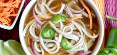 a bowl of soup with noodles, carrots and celery on the side