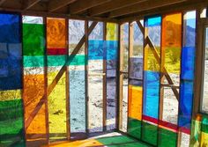 an open room with colorful stained glass walls and windows on the outside, in front of a mountain range