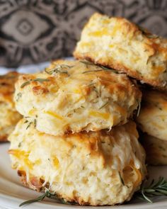 biscuits with cheese and herbs are stacked on top of each other in a white plate