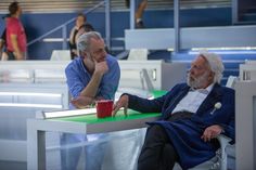 an older man sitting at a table with a red cup