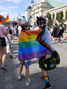 two people dressed up in costumes and holding a rainbow flag