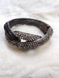 This piece is a gorgeous newer vintage piece, I would estimate to be from aprox the 90s. The piecs is a clamper style bracelet in gunmetal color. The piece is full of clear, grey metallic and black rhinestones. The inside measures aprox 6.75 inches. Please see all pictures on this piece for a better description and sizing. 13 Evening Rhinestone Bangle Bracelets, Evening Bangle Bracelets With Rhinestones, Evening Rhinestone Bangle Bracelet, Glamorous Evening Crystal Bangle Bracelet, Silver Bling Cuff Bracelet For Evening, Metal Bangle With Bling For Party, Silver Metal Crystal Evening Bracelet, Rhinestone Cuff Bracelet For Evening, Silver Metal Crystal Bracelet For Evening