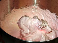 a metal bowl filled with pink frosting on top of a stove