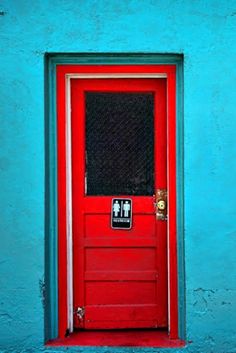 a red door on a blue wall with a sign that says no to peeing