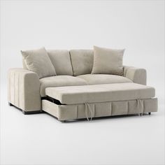 a white couch with pillows on it and a pull out bed in the back corner