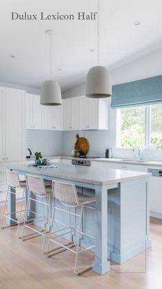 a large kitchen with white cabinets and blue counter tops, along with two bar stools