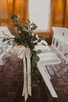 a bouquet of flowers sitting on top of a white chair next to a table with chairs in the background