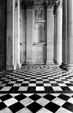 an old black and white photo of a room with columns, checkered flooring and walls