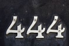 four metal numbers are shown on a black surface