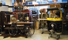 an old fashioned bicycle is parked in a room with many items on the walls and floor