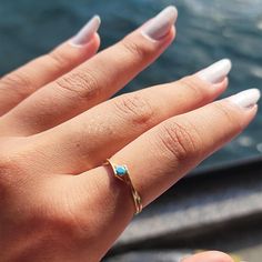 a woman's hand with white nails and a gold ring on her left hand