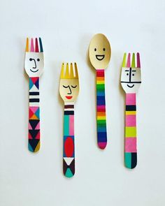 three wooden spoons with faces painted on them and forks in the shape of people's heads